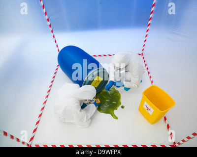 Vista superiore di due specialisti wearind bianco tute di protezione e maschere antigas la raccolta di campioni da una fuoriuscita di liquido da un blu Foto Stock