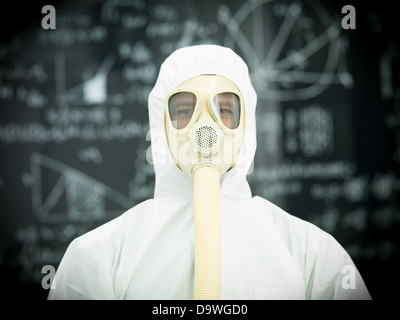 Persona in abbigliamento protettivo con maschera a gas di fronte a una lavagna con grafica e formule scritto su di esso in Chalk Foto Stock