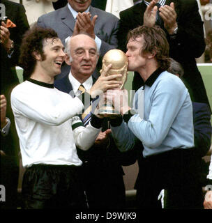 Ridendo team capitano Franz Beckenbauer è la holding ha vinto la World Cup e il portiere Sepp Maier è baciare il trofeo. DFB presidente Hermann Goessmann sta guardando. La squadra nazionale di calcio tedesca vince il 1974 FIFA World Cup finale 2:1 contro i Paesi Bassi a Monaco di Baviera stadio olimpico in Germania. Foto Stock