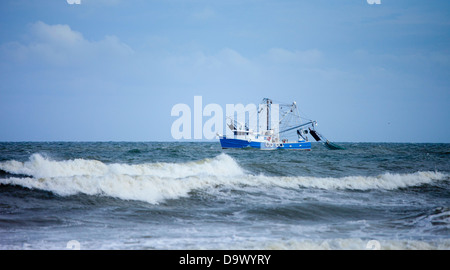 Barca da gamberetti trascinando net in mare mosso Foto Stock