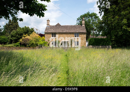 Percorso falciata attraverso erba lunga che conduce fino a Cotswold cottage in pietra. Wyck Rissington, Cotswolds, Gloucestershire, Inghilterra Foto Stock