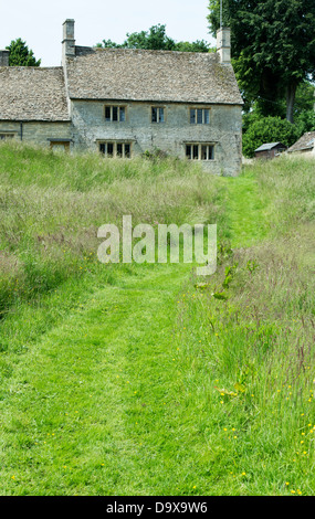 Percorso falciata attraverso erba lunga che conduce fino a Cotswold cottage in pietra. Poco Barrington, Cotswolds, Gloucestershire, Inghilterra Foto Stock