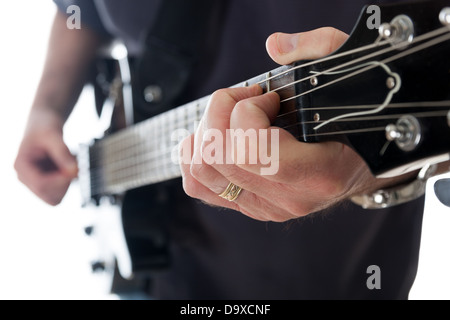 Vista ravvicinata della mano sinistra di un uomo diteggiatura una corda sulla tastiera di una chitarra elettrica. Foto Stock