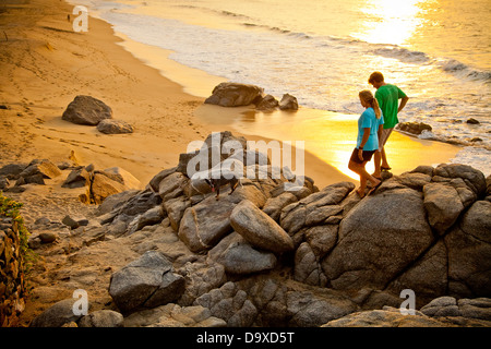 Coppia con cane escursioni sulla spiaggia spiaggia di roccia Foto Stock