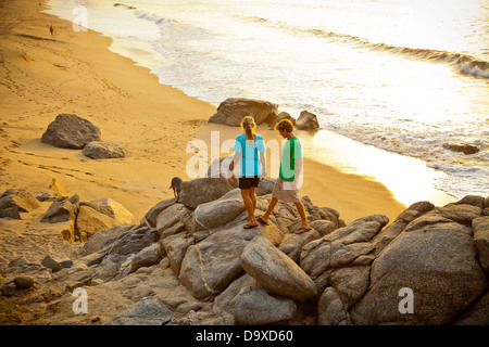 Coppia con cane escursioni sulla spiaggia spiaggia di roccia Foto Stock