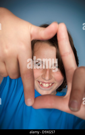 Sorridendo ragazzo caucasico che guarda attraverso una cornice fatta con le mani. Foto Stock