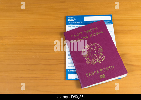 Passaporto italiano con UK carta di sbarco all'interno. Isolato sul modello in legno. Foto Stock