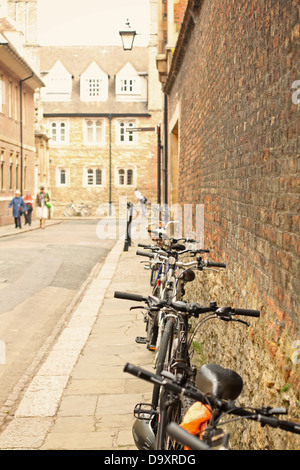 Una fila di biciclette parcheggiate contro un muro di mattoni in Cambridge. Foto Stock