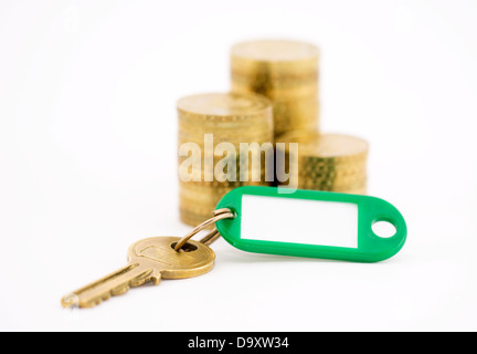 Chiave con monete isolato su bianco Foto Stock