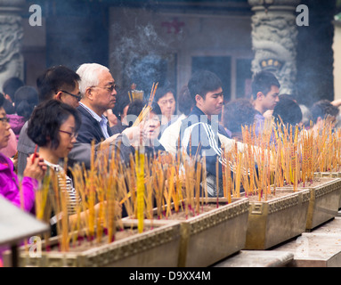 dh Wong Tai Sin Temple WONG TAI SIN HONG KONG Cina adoratori joss bastoni tempio santuario cinese persone joss bastone urns culto taoista Foto Stock