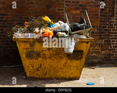 Saltare riempito di rifiuti domestici al di fuori di una casa contenuti includono un cucchiaio e tabella Foto Stock