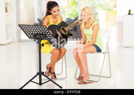 Giovane e bella ragazza preteen avente lezione di chitarra a casa Foto Stock