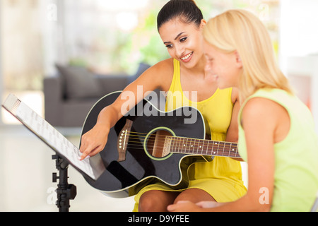 Piuttosto insegnante di musica di tutoraggio ragazza giovane a suonare la chitarra Foto Stock