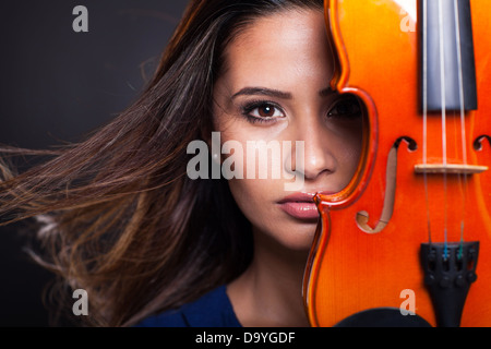 Ritratto di donna graziosa dietro un violino su sfondo nero Foto Stock