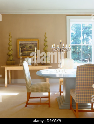 Verifica sedie imbottite in moderni tavolo ovale in beige paese sala da pranzo con fodera topiaria da sul tavolo console Foto Stock