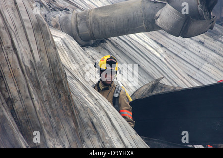 Un vigile del fuoco nel mezzo di un edificio è crollato da un incendio Foto Stock