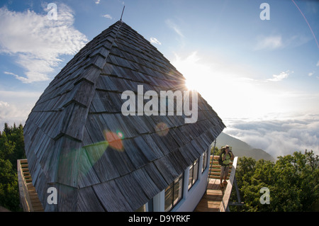 Una donna backpacker guardando attraverso il binocolo dalla manopola verde Firetower, Pisgah National Forest, Asheville, North Carolina. Foto Stock