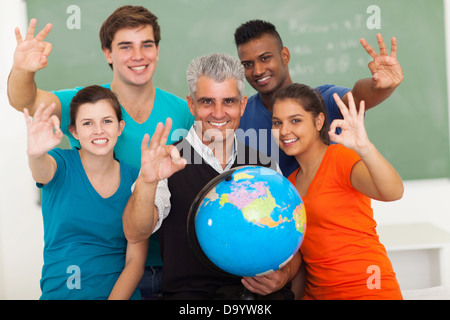 Allegro di alta scuola geografia studenti e docenti dando segno OK con la mano in aula Foto Stock