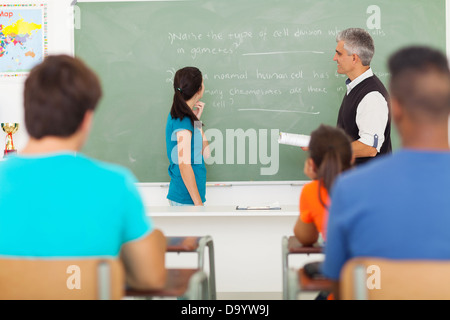 High School girl stati chiamati alla lavagna da senior insegnante durante la lezione di biologia Foto Stock