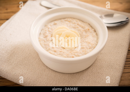 Ciotola di porridge guarnita con fette di banana. Foto Stock