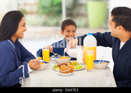 Padre amorevole versando il latte nel suo figlio corn flakes durante la prima colazione Foto Stock