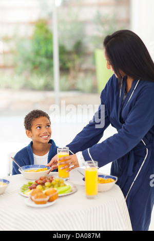 Madre premurosa dando figlio prima colazione Foto Stock