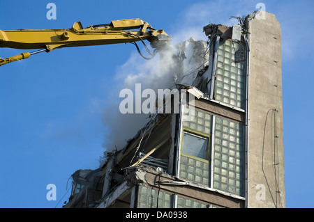 Grande giallo, escavatore bulldozer la demolizione di un edificio alto in una giornata di sole Foto Stock