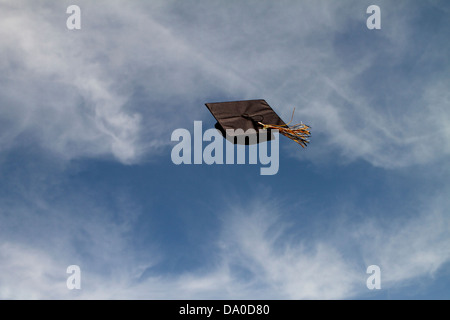 Tappo di graduazione volare attraverso l'aria a una cerimonia di laurea contro un cielo blu con nuvole bianche, con successo il volo libero! Foto Stock