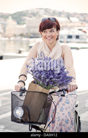 Le donne in sella ad una bici retrò con fiori di lavanda in basket Foto Stock