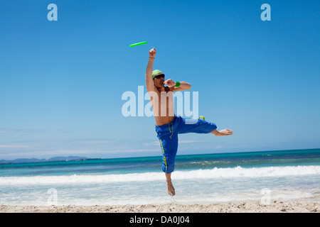 Attraente uomo giocando frisby sulla spiaggia in estate sport fitness jump Foto Stock