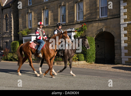 Ai cavalli da corsa essendo cavalcato attraverso Middleham, North Yorkshire, sulla strada del ritorno dalla formazione galoppa. Foto Stock