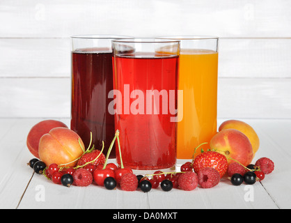 Succo di bacca in bicchieri con frutti di bosco freschi su sfondo di legno Foto Stock