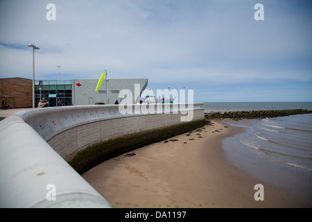 Porth Eirias Centro, Colwyn Bay mostra creative shot di mare difese con vetro e metallo & building in background Foto Stock