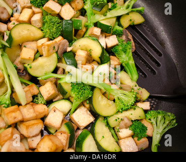 Cuocere una padella con tofu, broccoli e zucchine (zucchine). Una frittura sana vegana a base vegetale. Foto Stock