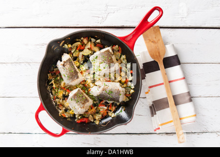 Nasello e verdure in una padella in un tavolo bianco overhead shot Foto Stock