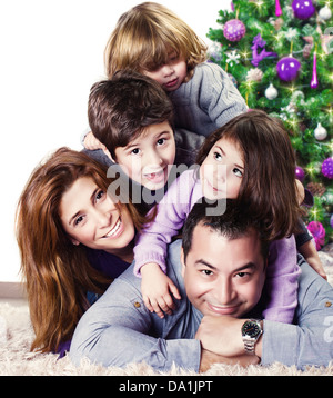 Closeup ritratto della famiglia allegra sdraiati vicino a albero di Natale a casa, genitori felici con tre bambini festeggiare il nuovo anno Foto Stock