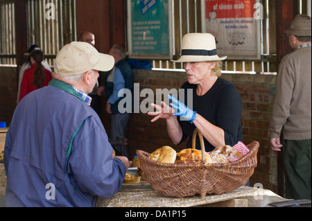 Donna che indossa hat vendendo torte sulla sua stallo a mensile del mercato degli agricoltori in Malton Ryedale North Yorkshire England Regno Unito Foto Stock