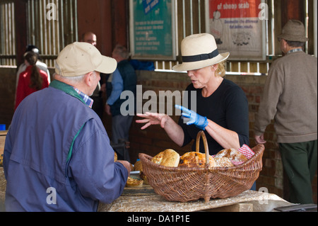 Donna che indossa hat vendendo torte sulla sua stallo a mensile del mercato degli agricoltori in Malton Ryedale North Yorkshire England Regno Unito Foto Stock