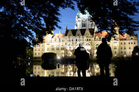 Passanti guardare il illuminato di facciata del nuovo municipio con lo stagno Maschteich davanti ad Hannover, Germania, 29 giugno 2013. Foto: PETER STEFFEN Foto Stock