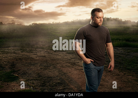 L'uomo cammina attraverso il campo con tramonto in background Foto Stock