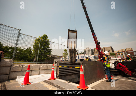 Funzionamento nel campo dei lavoratori dalla NYC Dipartimento di Protezione Ambientale sostituire le schermate in un dispositivo di controllo dell'inquinamento Foto Stock