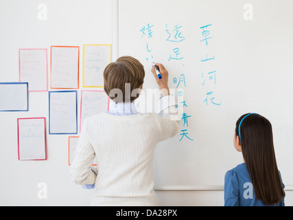 Insegnante e schoolgirl (8-9) scrivendo a whiteboard Foto Stock