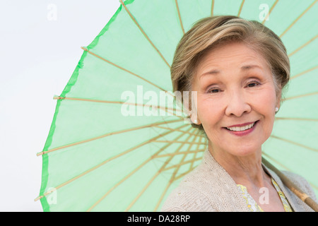 Ritratto di donna senior azienda ombrellone verde Foto Stock