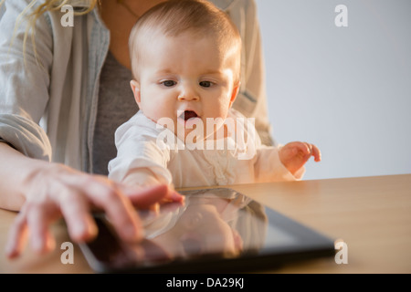 Madre e figlia bambino (6-11 mesi) giocando con tavoletta digitale Foto Stock