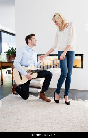 Uomo a suonare la chitarra nella parte anteriore della donna Foto Stock