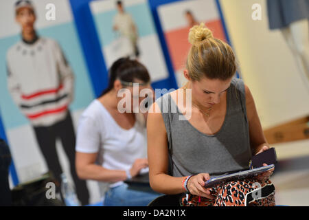 Due visitatori il lavoro durante la fiera di moda "Bread & Butter" presso l'ex aeroporto Tempelhof di Berlino su un computer portatile e un computer tablet, Germania, 02 luglio 2013. Le presentazioni della primavera/estate 2014 le collezioni si svolgerà dal 02 al 04 luglio 2013. Foto: Marc Tirl/dpa +++(c) dpa - Bildfunk+++ Foto Stock