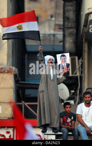 Un uomo nel tradizionale egiziana onde del vestito di una bandiera e detiene un poster a una manifestazione contro il Presidente egiziano Mursi a Piazza Tahrir al Cairo, Egitto, 29 giugno 2013. Il Presidente egiziano Mursi celebrerà il primo anno in carica il 30 giugno 2013 tra le manifestazioni contro il suo governo islamico. Foto: MATTHIAS TOEDT Foto Stock