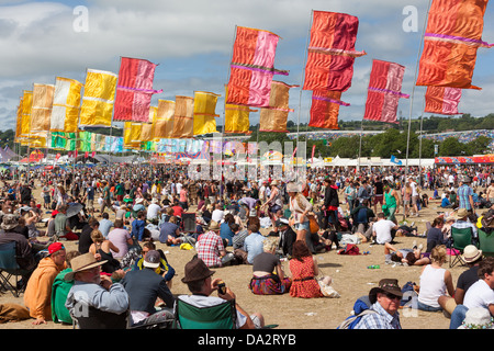 FESTIVAL DI glastonbury, Regno Unito - 30 Giugno 2013 : la folla sedersi sotto il sole sotto le bandiere colorate all'altro stadio Foto Stock