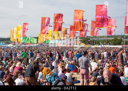 FESTIVAL DI glastonbury, Regno Unito - 30 Giugno 2013 : la folla sedersi sotto il sole sotto le bandiere colorate all'altro stadio Foto Stock