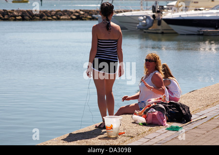 Donne pescato granchi presso il porto di Poole in giugno Foto Stock